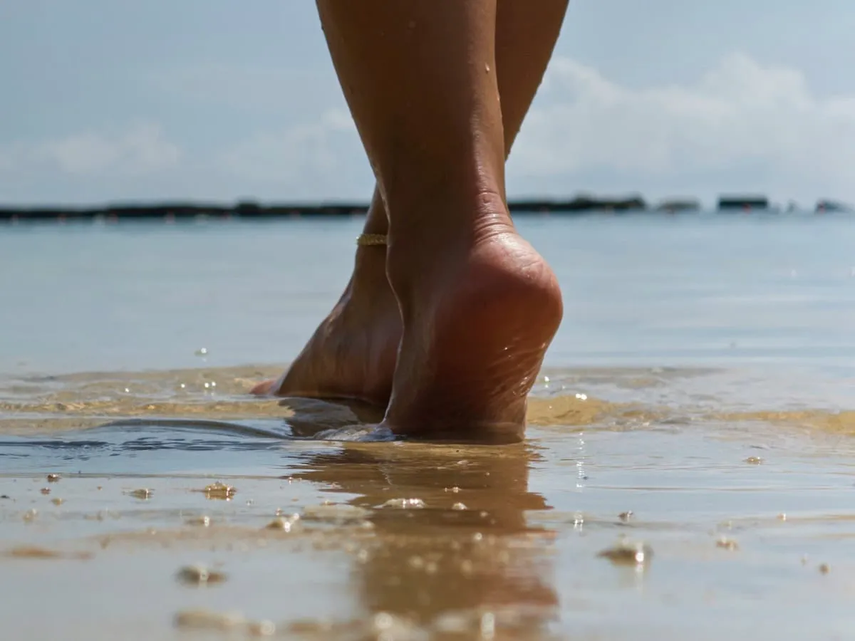 Bare feet walking along a wet beach