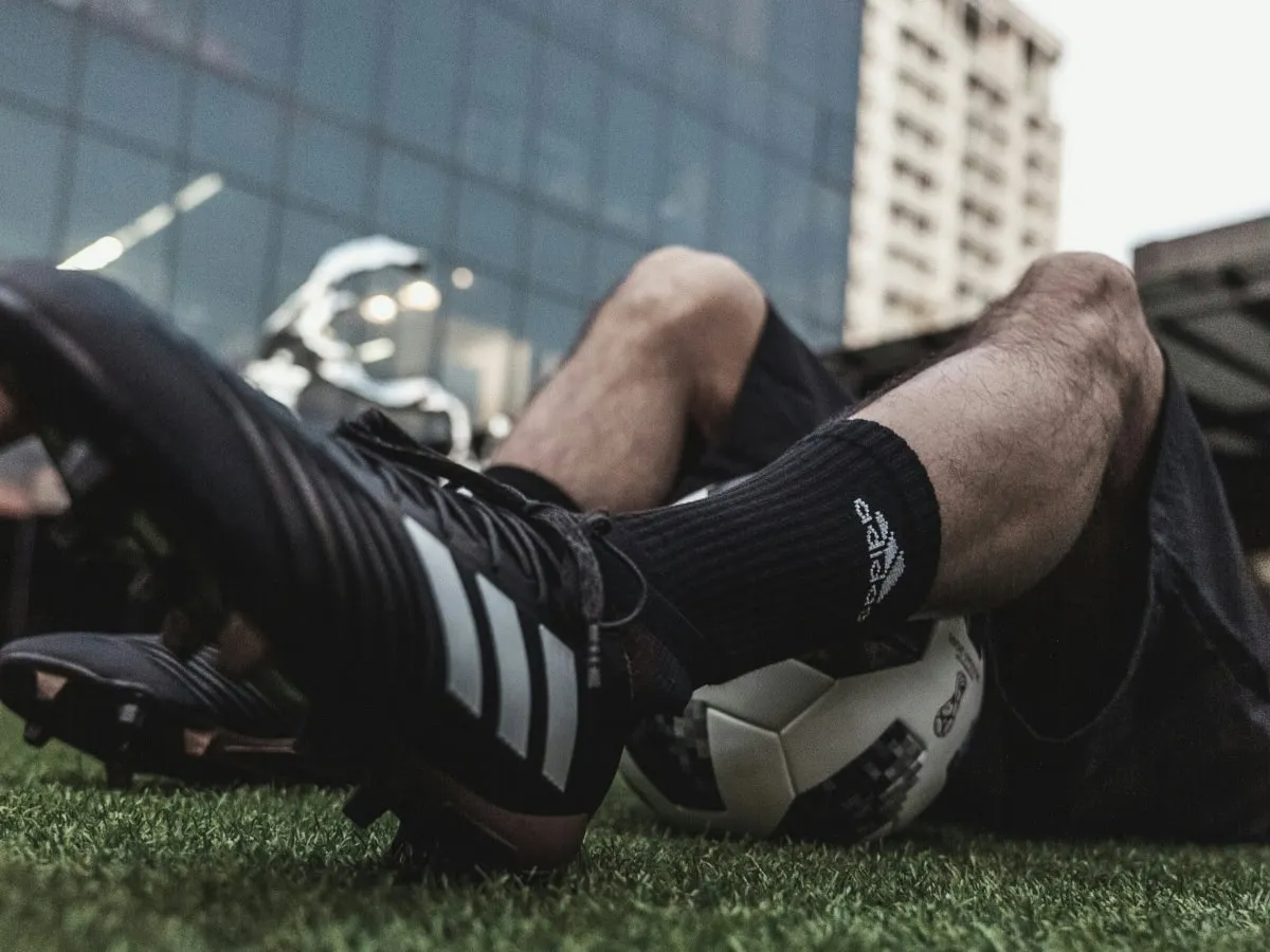 Footballer resting on artificial grass with boots and a ball