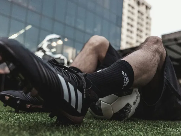 Footballer resting on artificial grass with boots and a ball